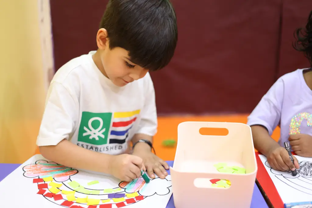 Child doing a colouring activity with crayons at a classroom table