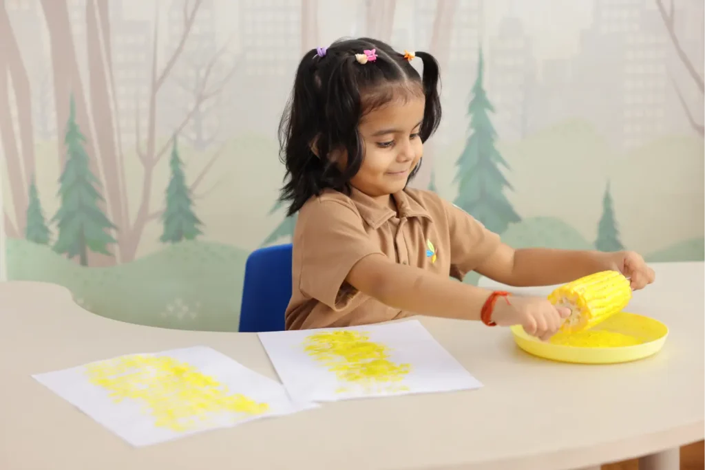 Young girl painting with yellow paint at a table in the classroom