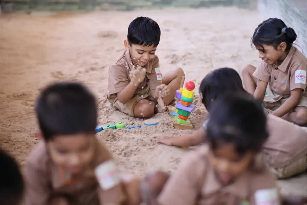 Young children playing and exploring in the sand outdoors