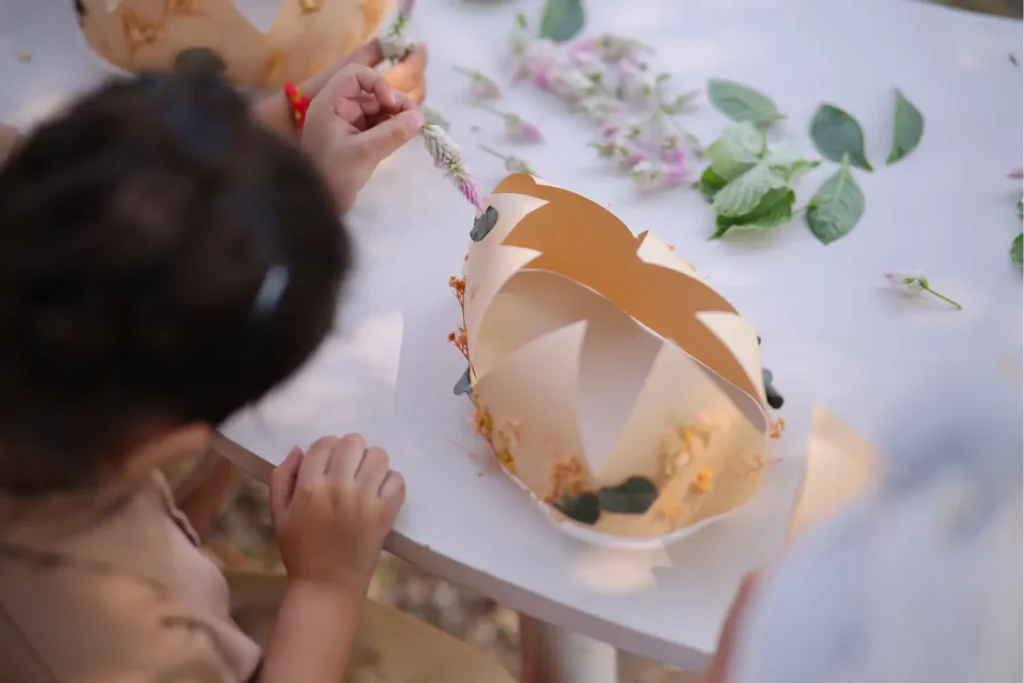 Child making a craft with leaves and natural materials during a nature activity