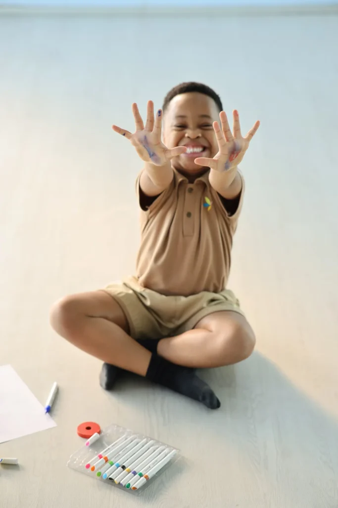 Smiling boy showing his painted hands after messy play at Williez Preschool, India