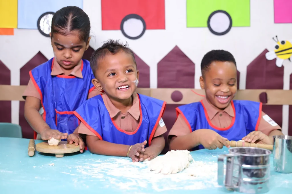 Smiling children in art aprons enjoying a classroom activity at Williez Preschool, India