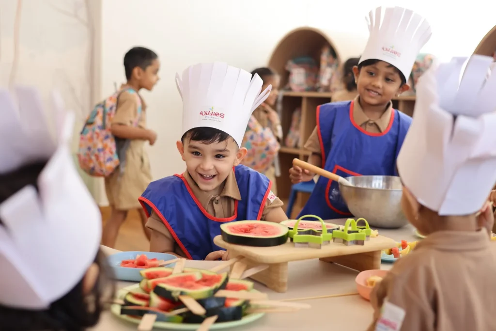 Little chefs preparing fruit during a cooking activity at Williez Preschool, India