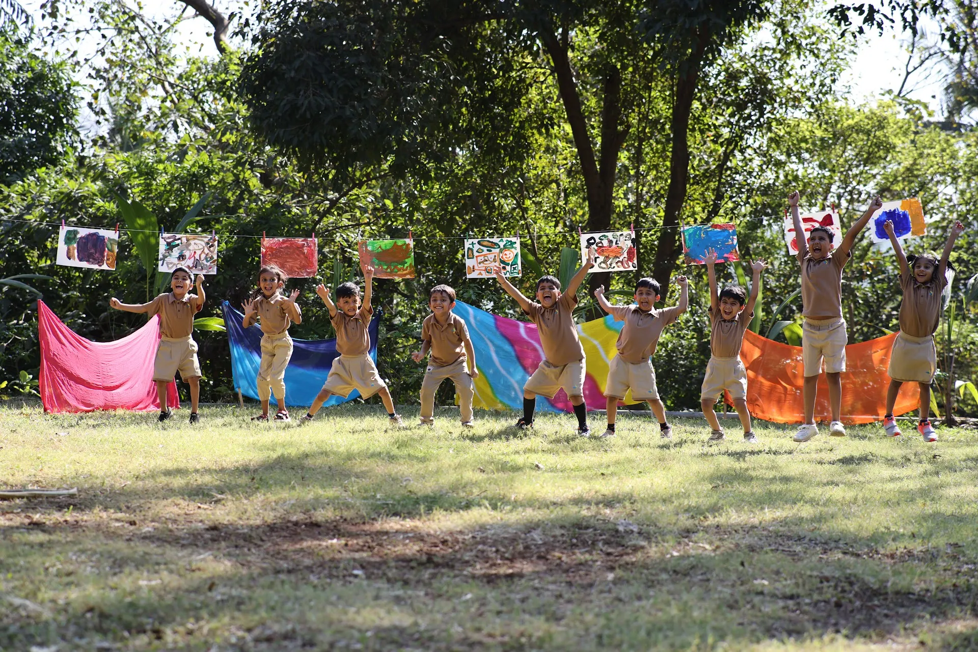 Children proudly showing their paintings in the garden at Williez Preschool, India