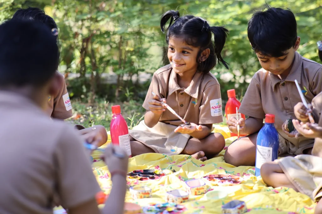 Two girls painting together outdoors at Williez Preschool, India