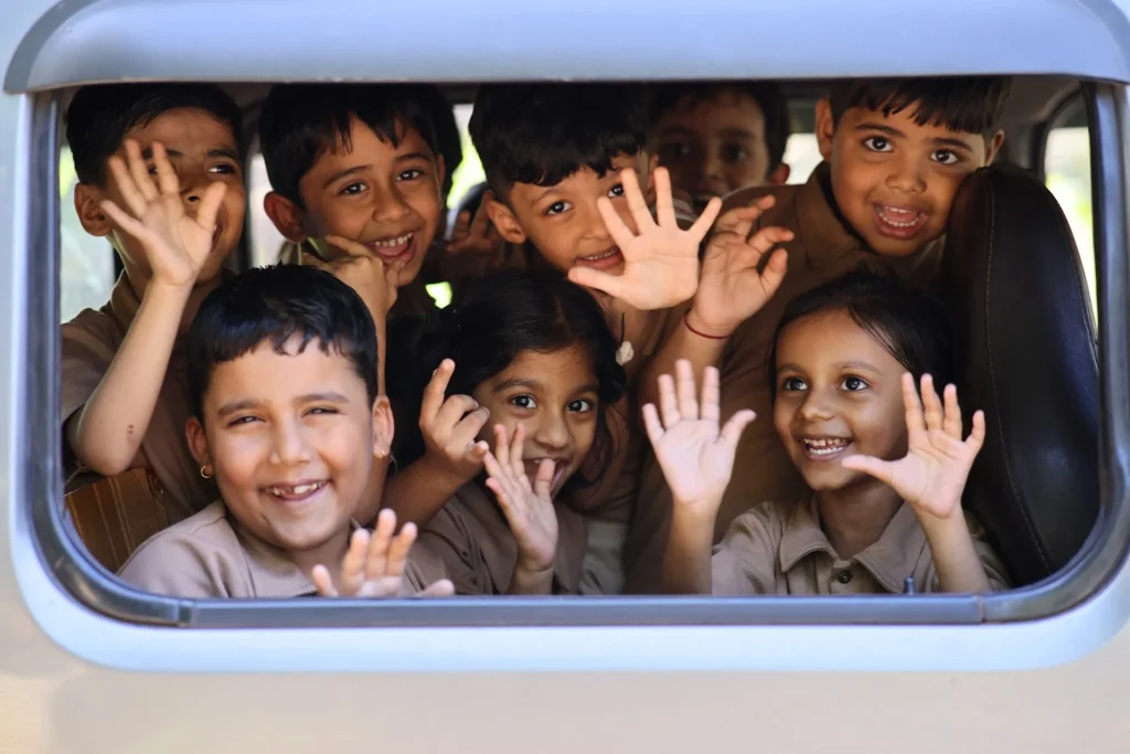 Group of happy children waving and smiling at Williez Preschool, India