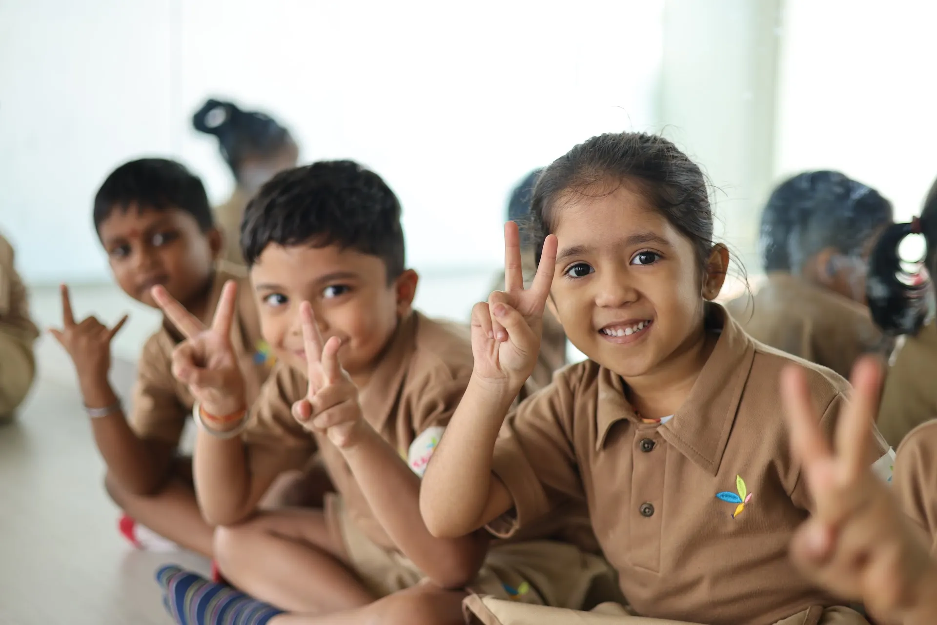 Happy friends showing peace signs in class at Williez Preschool, India